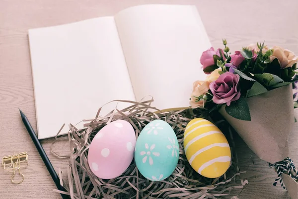 粉彩和五颜六色的复活节蛋在巢和花束与空白笔记本在木背景 快乐复活节假期的概念 — 图库照片