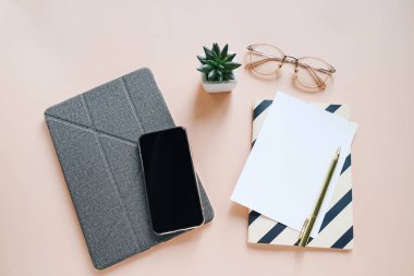 Tablet PC ve pembe renk arka plan üzerinde beyaz kağıt ile minimal Kırtasiye ve akıllı telefon ile çalışma masası 