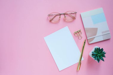 Kağıt ve bitki pembe renk arka plan ile minimal Kırtasiye ve Notebook ile çalışma masası 