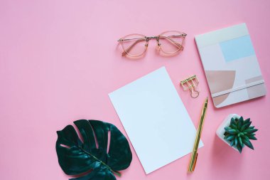 Kağıt ve pembe renk arka planda tropikal yaprak ile minimal Kırtasiye ve Notebook ile çalışma masası 