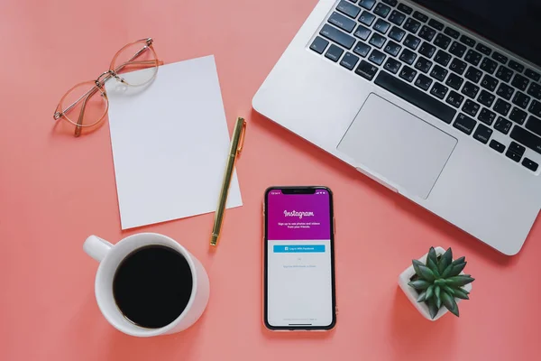 フラットレイワークスペースデスクとアップルの Iphone ピンクの背景にノートパソコンとコーヒーカップで画面上の Instagram アプリケーションで — ストック写真