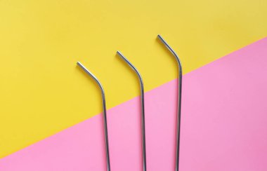 Parlak pembe ve sarı arka plan, sürdürülebilir yaşam tarzı ve sıfır atık kavramı üzerinde yeniden kullanılabilir paslanmaz çelik pipetdüz yatıyordu