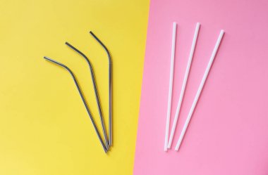 Parlak pembe ve sarı arka plan, sürdürülebilir yaşam tarzı ve sıfır atık kavramı üzerinde plastik pipetler ile yeniden kullanılabilir paslanmaz çelik pipetdüz yatıyordu