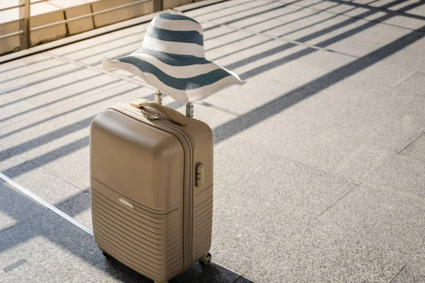 suitcase with summer hat at airport departure lounge, travel and vacation concept