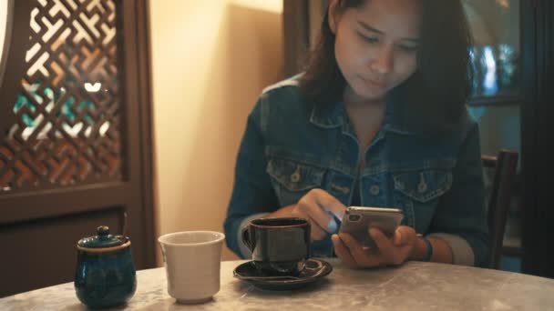 Ασιατικές Γυναίκα Χρησιμοποιώντας Smartphone Και Ποτό Καφέ Στο Καφέ — Αρχείο Βίντεο