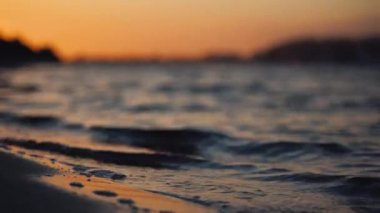 Parlak turuncu günbatımında dalgalı göl yüzeyinin resimsel görüntüsü 