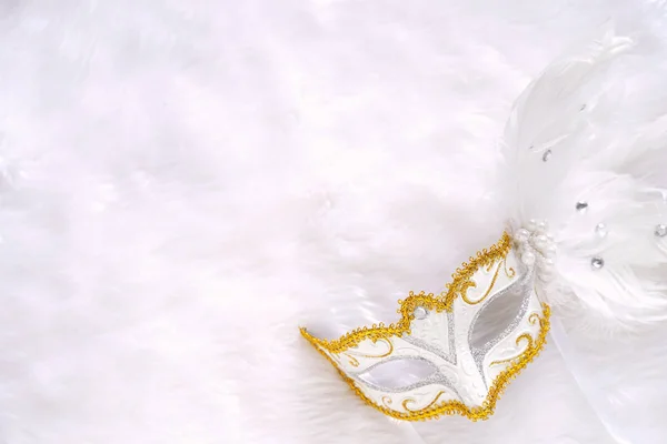 Top view of white fancy mask for party celebration on white soft fur fabric background, holiday and carnival event