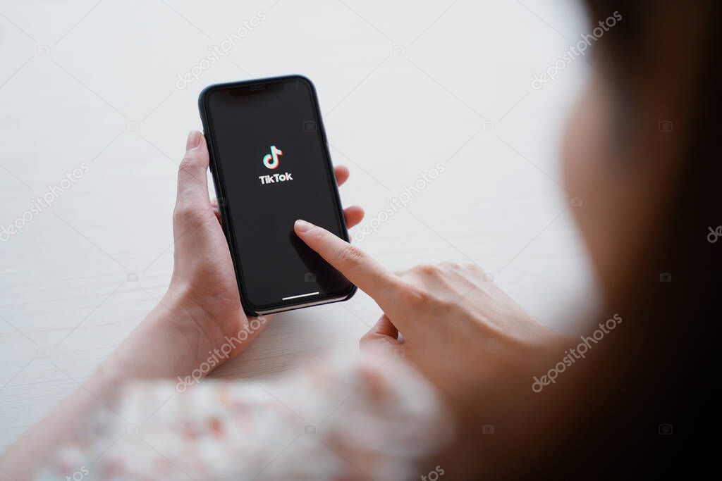 Nakhon Ratchasrima, Thailand - May 25, 2020 : woman using iPhone XS showing Tik Tok application on screen, Tik tok is popular social media network and entertainment