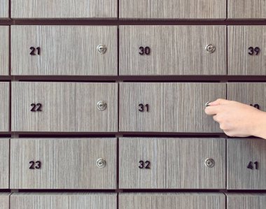 Dairede ahşap posta kutusu açan kadın eli.