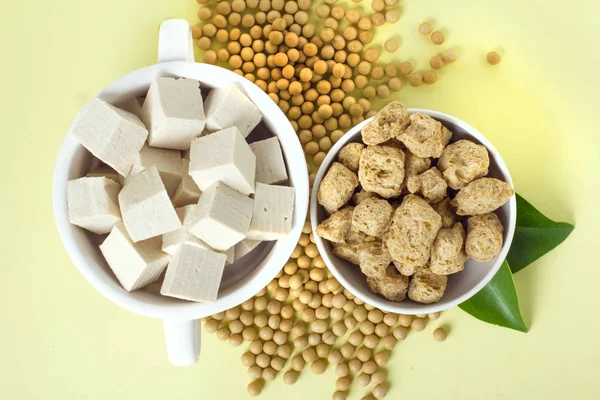 Organic soy products on light yellow background: soy beans, tofu and soy meat