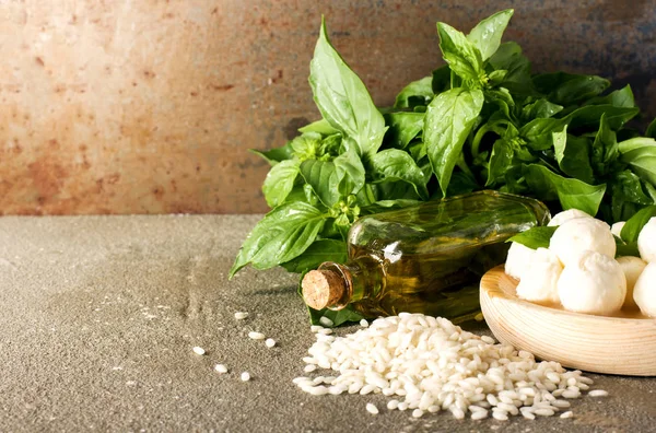 Küçük topları mozzarella peyniri ile fesleğen yaprağı, pirinç arborio ve rustik zemin üzerine zeytin yağı
