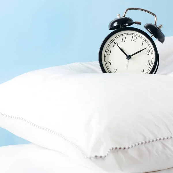 Reloj despertador en las almohadas. Concepto publicitario, espacio de copia — Foto de Stock