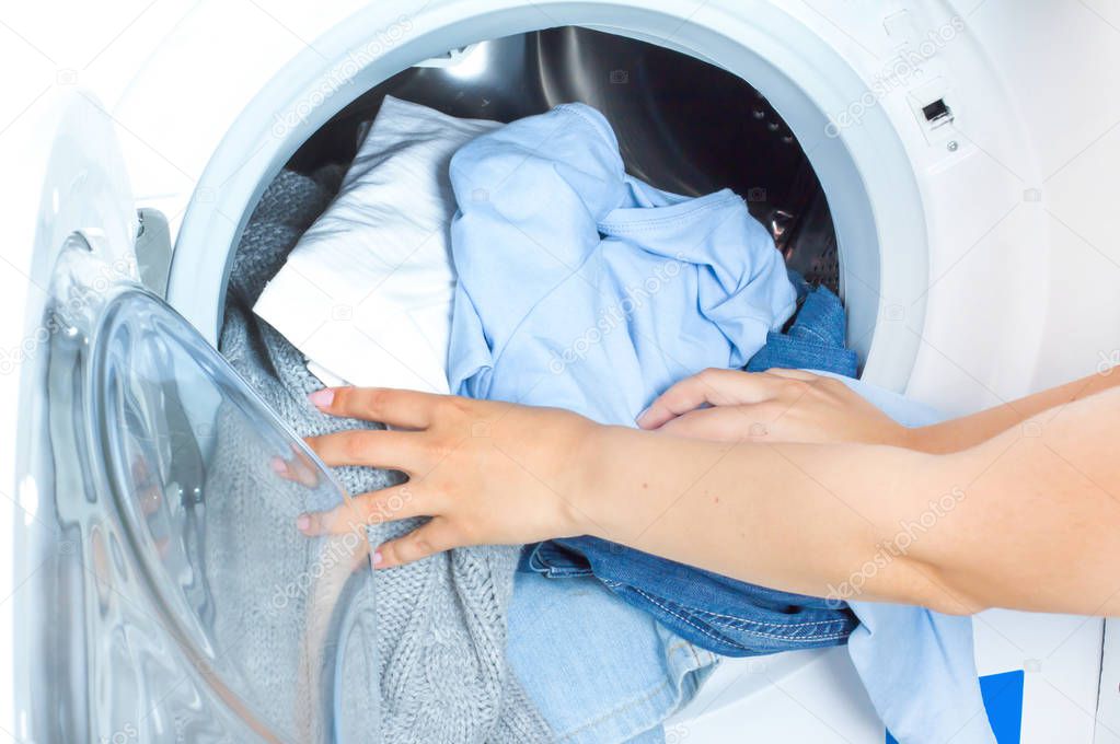 Preparing the wash cycle. Washing machine, hands and clothes