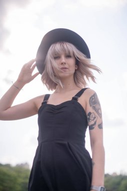 Güzel genç kadın dövme ve siyah elbise poz ile 