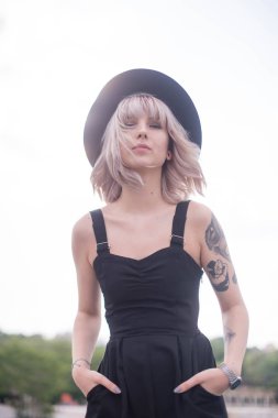 Güzel genç kadın dövme ve siyah elbise poz ile 