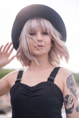 Güzel genç kadın dövme ve siyah elbise poz ile 