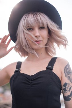 Güzel genç kadın dövme ve siyah elbise poz ile 