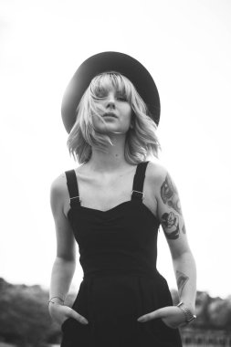 Güzel genç kadın dövme ve deniz arka plan üzerinde poz siyah elbise ile