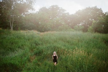 Güneşli bir gün alanında siyah elbiseli Genç Sarışın hipster kadın portresi. 