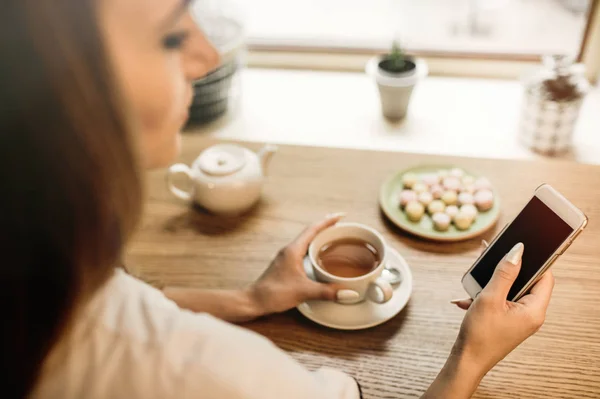 Vrouw met telefoon en hete thee — Stockfoto