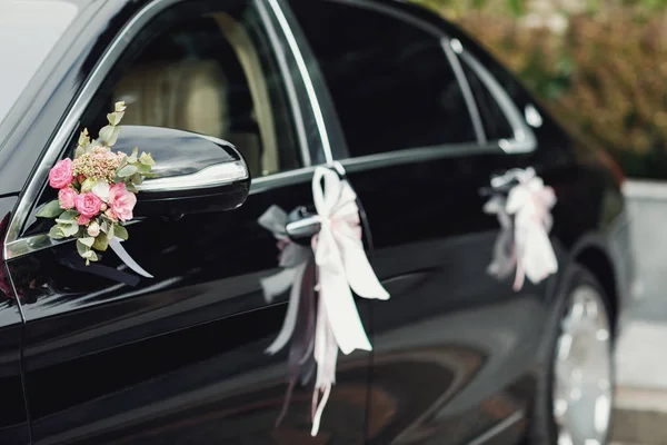 black wedding car decorated with white roses
