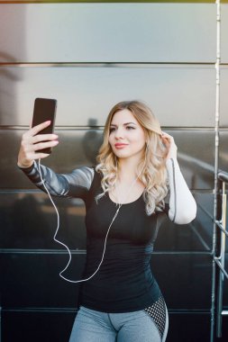 Bir egzersiz yaptıktan sonra bir selfie fotoğraf çekmek için bir akıllı telefon kullanan kadın.