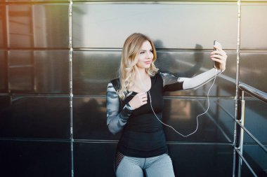 Bir egzersiz yaptıktan sonra bir selfie fotoğraf çekmek için bir akıllı telefon kullanan kadın.