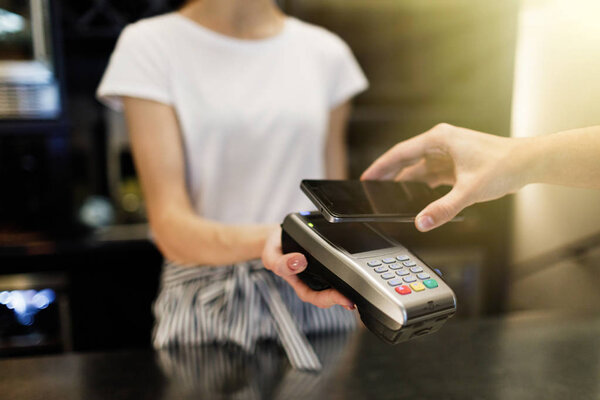 Man using mobile payment in a coffee shop. Contactless smartphone payment.