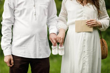 Mutlu ve genç hamile çift doğada sarılma. Onların gelecekteki bebek tutan hamile çift çizme.