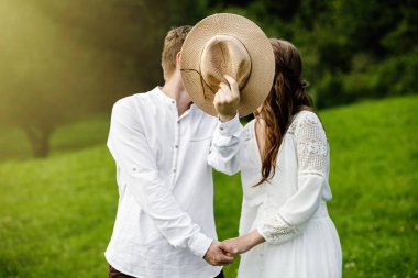 Hamile kadın ve erkek yaz Park'ta poz. Güzel hippi çift ayakta Park.