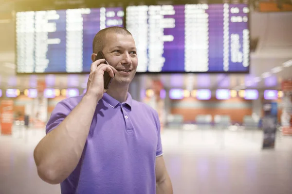 man with phone in airport. Young man in airport using smartphone .