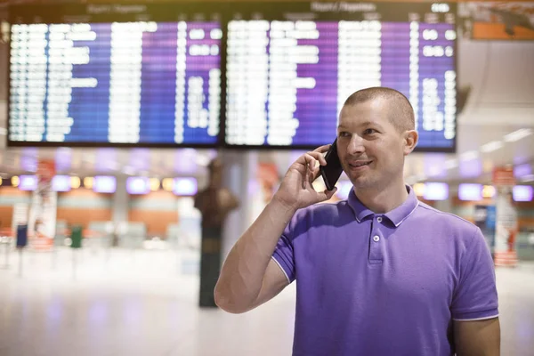 man with phone in airport. Young man in airport using smartphone .