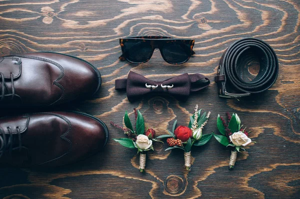 The groom\'s accessories. Leather shoes on  background with a bow tie and cuff links , shoes and flowers. Top view , bokeh.