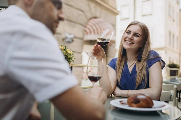 Pareja alegre en un restaurante con copas de vino tinto. Joven — Foto de Stock