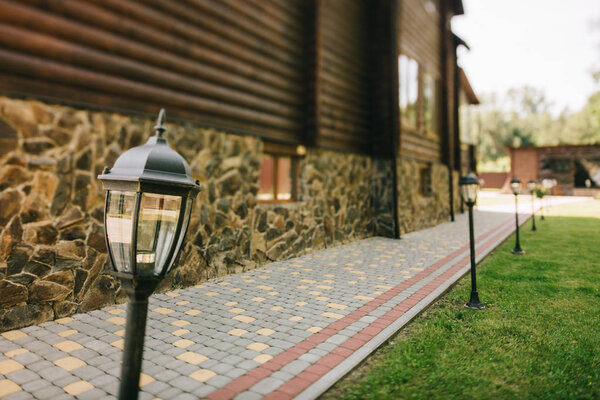 Уличные кованые металлические фонари на ухоженном коттедже с зеленой травой
 