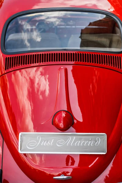 Wedding  car decorated with  sing JUST MARRIED. Red retro car with just married sign. Vintage wedding car with just married sign and cans attached.