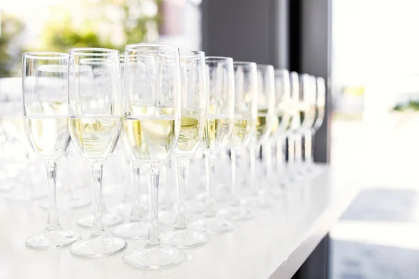 Full cold champagne flutes stand between buckets on dinner table