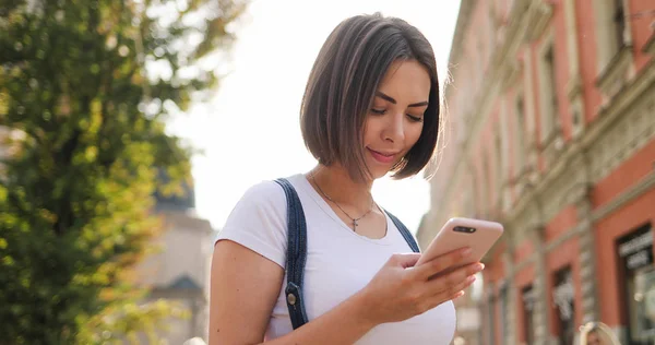 Retrato de niña positiva joven utilizando el dispositivo de teléfono inteligente moderno t — Foto de Stock