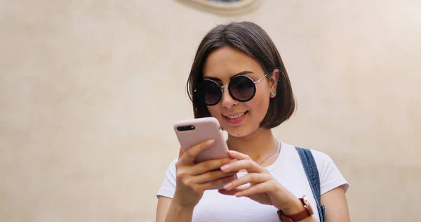 Retrato de niña positiva joven utilizando el dispositivo de teléfono inteligente moderno t — Foto de Stock