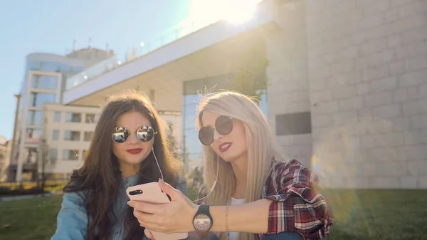 Dos chicas hipster atractivas usando un teléfono inteligente . —  Fotos de Stock