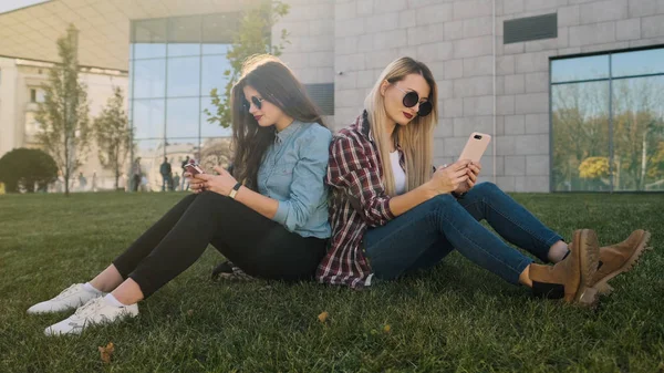 Dos chicas hipster atractivas usando un teléfono inteligente . —  Fotos de Stock