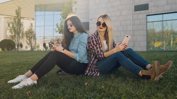 Dos chicas hipster atractivas usando un teléfono inteligente . —  Fotos de Stock