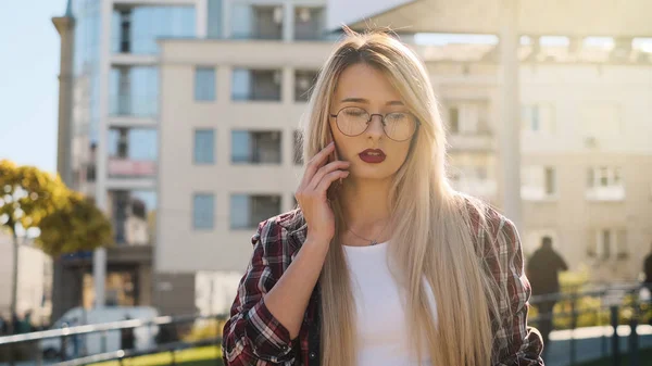 Utomhus porträtt en blond ung kvinna som talar genom sin smartphone — Stockfoto