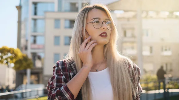 На відкритому повітрі портрет блондинки молода жінка розмовляє зі своїм смартфоном — стокове фото