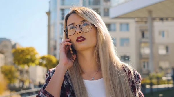 Retrato al aire libre de una joven rubia hablando con su smartphone —  Fotos de Stock