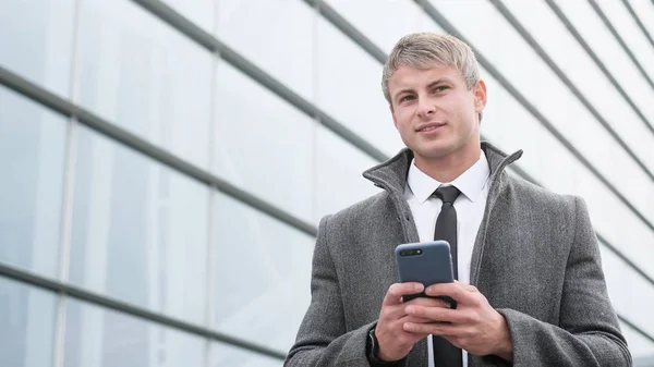 Handsome businessman in a city. Portrait of handsome business man using smartphone  in the city.