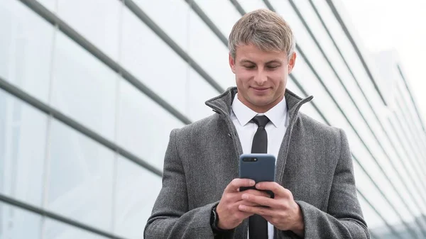 Handsome businessman in a city. Portrait of handsome business man using smartphone  in the city.