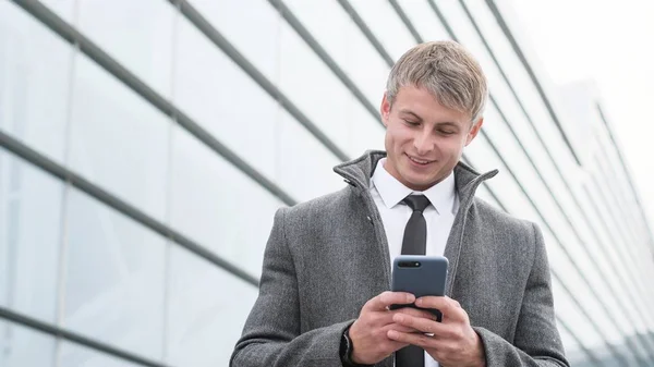 Handsome businessman in a city. Portrait of handsome business man using smartphone  in the city.