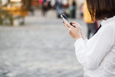 Cep telefonuyla dururken bulanık sokak arka plan üzerinde güzel bir kadın portresi. Bir uygulama akıllı telefonunu kullanarak kızlar.