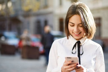 Cep telefonuyla dururken bulanık sokak arka plan üzerinde güzel bir kadın portresi. Bir uygulama akıllı telefonunu kullanarak kızlar.